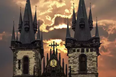 Dramatic view of a historic building with gothic spires silhouetted against a sunset. Ideal backdrop for a memorable team-building event, inspiring collaboration and creativity.