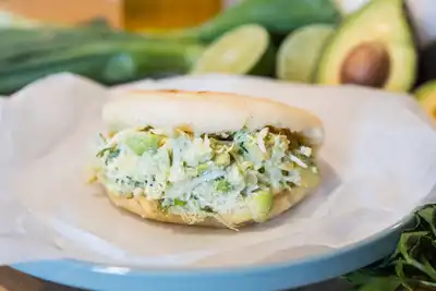 A fresh arepa filled with avocado chicken salad, displayed on a plate, highlighting culinary team-building activities perfect for HR professionals planning engaging events.