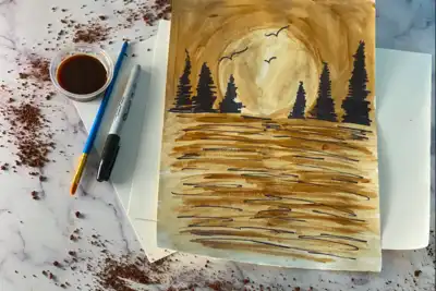 A creative team-building art project featuring a watercolor painting of a serene landscape with trees and birds. A paintbrush, a cup of brown paint, and a black marker are placed beside the artwork on a marble surface, hinting at a collaborative and artistic team activity ideal for HR professionals looking to enhance team cohesion.