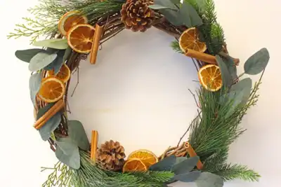 A handcrafted holiday wreath with pine branches, dried orange slices, eucalyptus leaves, cinnamon sticks, and pinecones. Ideal for a festive team-building decoration activity.