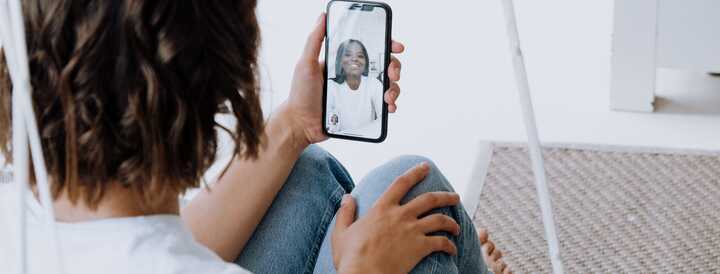 A person sitting comfortably while participating in a virtual meeting on a smartphone, illustrating a remote team-building event ideal for HR professionals looking to strengthen team connections.