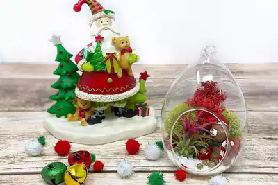 Festive holiday-themed decorations featuring a Santa ornament and a Christmas terrarium with colorful moss and a small bear. Ideal for HR professionals planning team-building activities, enhancing creativity and bonding during holiday events.